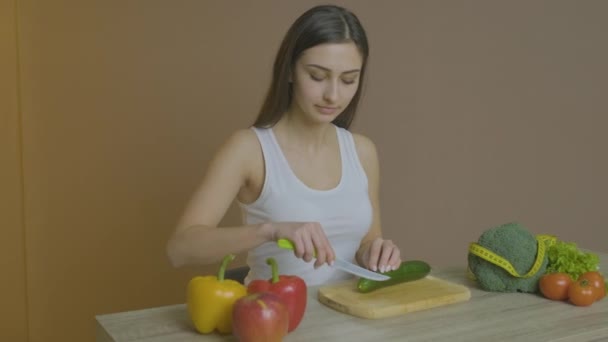 Femme assise à une table et tranche un concombre — Video