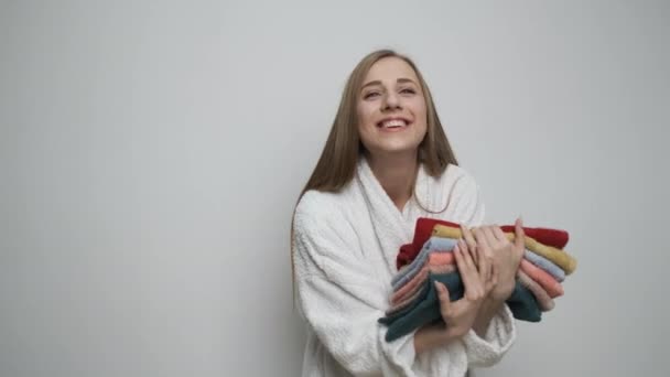 Menina bonito segura toalhas coloridas e espera na frente da câmera — Vídeo de Stock