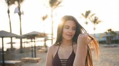 Avuç içlerinin yanında güzel bir kız saçını deniz kenarında düzleştirir.