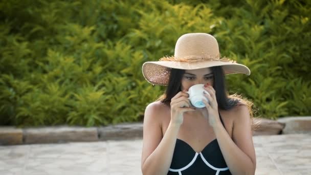 Girl in the pool enjoys coffee on a green background — Stock Video