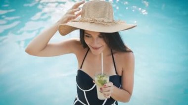 Şapkalı kadın kozmopolit kokteyliyle bilardo oynuyor.