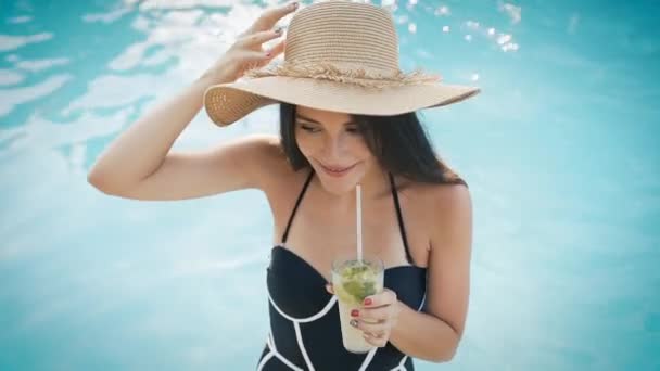 Mulher de chapéu relaxante na piscina com coquetel cosmopolita — Vídeo de Stock