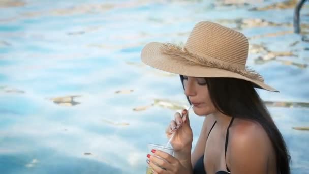 Kobieta w kapeluszu relaks na basenie z koktajlem kosmopolitycznym — Wideo stockowe