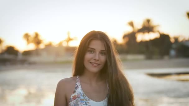 Chica con un sombrero posando delante de la cámara al atardecer — Vídeos de Stock