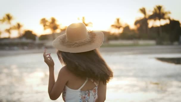 Flicka med hatt som poserar framför kameran vid solnedgången — Stockvideo