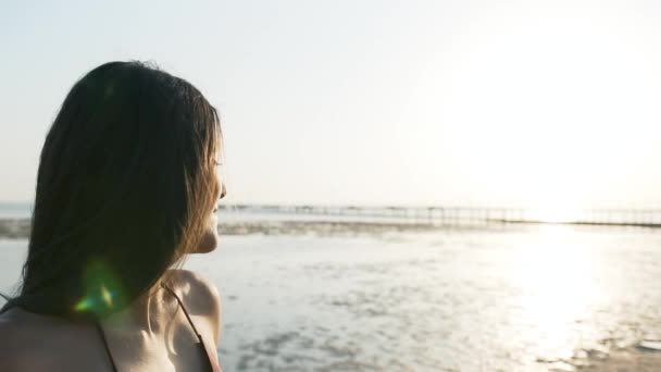 Hermosa chica cerca de las palmas endereza su cabello junto al mar — Vídeo de stock