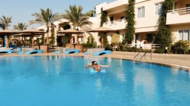 İnsansız hava aracı Mısır 'da bir havuzun üzerinde uçuyor. Yatağın üzerinde bir kadın yatıyor.