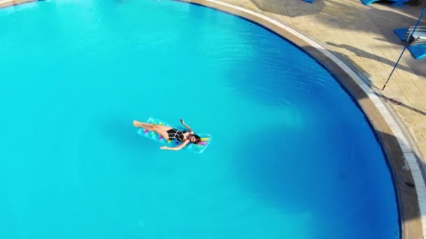 Drone flies over a pool in Egypt, where a woman swims on a mattress — Stock Video