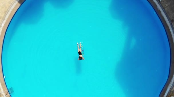 Drone vliegt over een zwembad in Egypte, waar een vrouw zwemt op een matras — Stockvideo