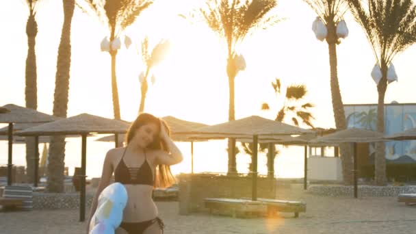 Chica con un colchón pasea por la playa cerca de palmeras — Vídeo de stock