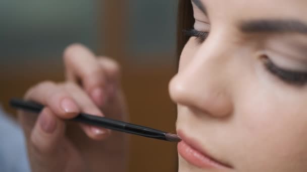 Hermosa chica está dibujando labios salón de belleza — Vídeo de stock