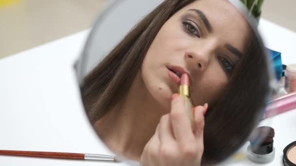 Meisje tekent haar lippen terwijl kijken in de spiegel — Stockvideo