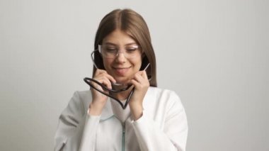 Kafkas görünümlü güzel kadın doktor kameraya gülümser ve bir stetoskopi tutar. İlaç. Sağlık