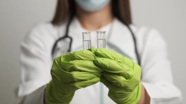 Maskeli ve eldivenli kız doktor test tüpleri tutuyor. Sağlık, sağlık