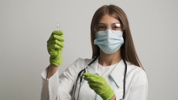 Een vrouwelijke arts met een masker en handschoenen houdt reageerbuisjes vast. Gezondheid, geneeskunde — Stockvideo