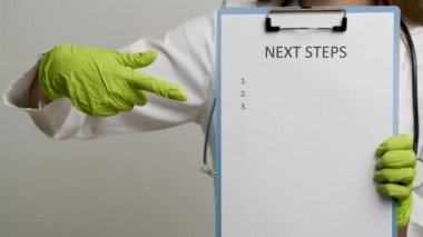 Tıp önlüklü kadın doktor bir sonraki adımda metnin olduğu bir klasör gösteriyor.