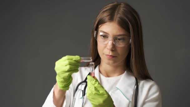 Niña médico de apariencia caucásica en guantes verdes sostiene tubos de ensayo. Salud, Medicina — Vídeos de Stock