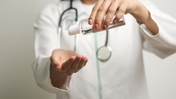 Doctor in goggles caucasian girl holds antiseptic in her hands and puts on her hands — Stock Video