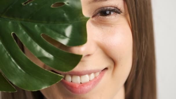 카메라 앞에 초록색 잎사귀가 있는 코카서스 계아름다운 소녀 — 비디오