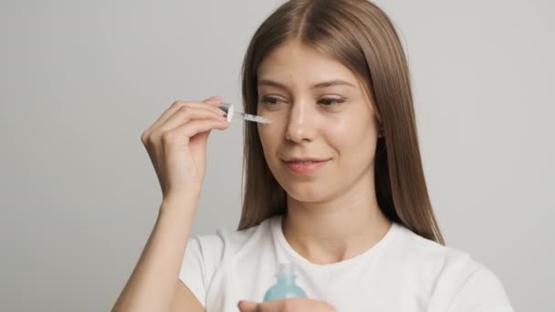 Linda chica de apariencia caucásica aplica crema facial — Vídeos de Stock