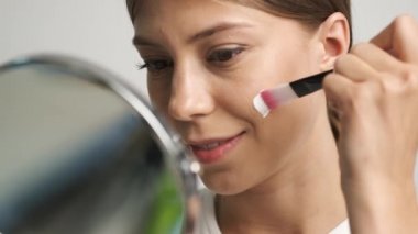 Kafkas görünümlü kız yüzüne krem sürüyor.