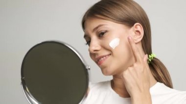 Kafkas görünümlü kız yüzüne krem sürüyor.