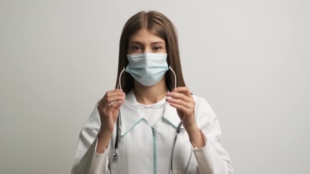 Mujer caucásica médico en gafas y estetoscopio mira a la cámara y endereza el cabello — Vídeos de Stock