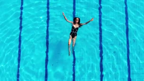 Beautiful girl swims in the pool and enjoys the scenery — Stock Video