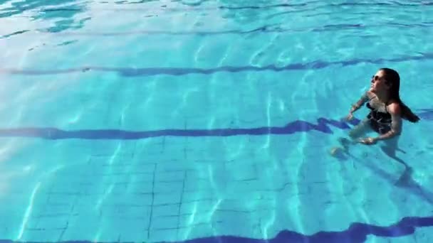 Beautiful women swims in the pool and enjoys the scenery — Stock Video