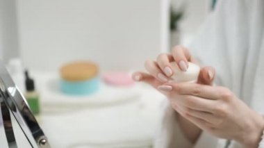 Kız parlak odada krem sürüyor.