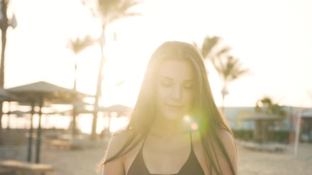 Красива дівчина біля долонь вирівнює волосся біля моря — стокове відео