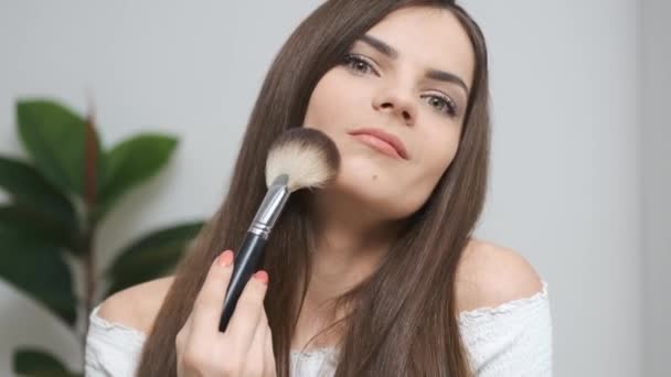 Девушка делает макияж глядя в зеркало — стоковое видео