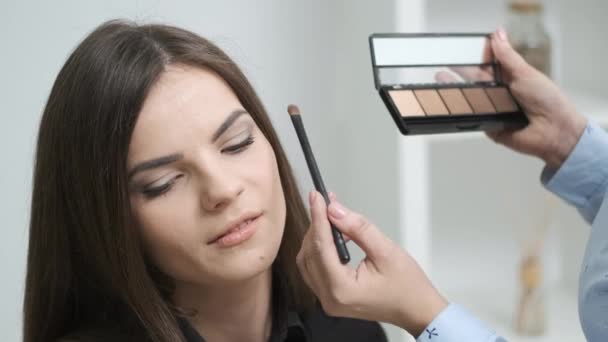 Mooi meisje doen make-up in schoonheid salon — Stockvideo