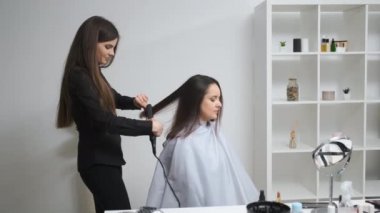 Güzellik salonunda saç maşasıyla saçını düzelten bir kız.