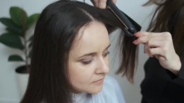 Güzellik salonunda saç maşasıyla saçını düzelten bir kız.