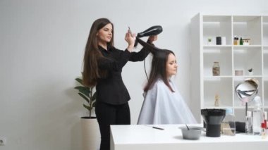 Güzellik salonunda saç maşasıyla saçını düzelten bir kız.