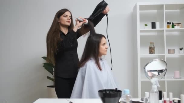 Chica alisando su cabello con rizador en un salón de belleza — Vídeo de stock