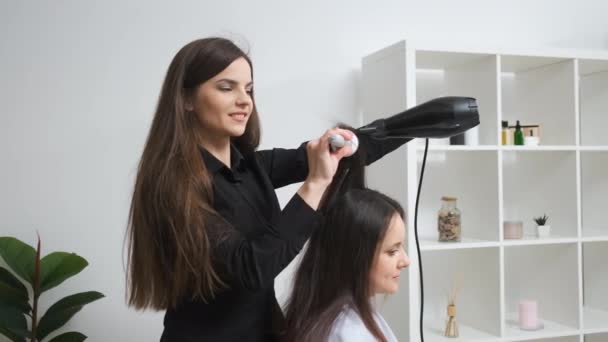 Девушка выпрямляет волосы щипцами в салоне красоты — стоковое видео