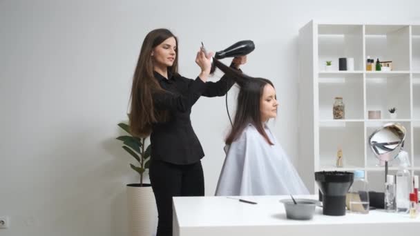 Menina alisando seu cabelo com ferro de ondulação em um salão de beleza — Vídeo de Stock