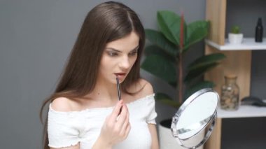 Güzel kız masada dudaklarını çizer.