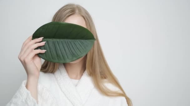 카메라 앞에 녹색 잎을 내고 있는 아름다운 소녀 — 비디오