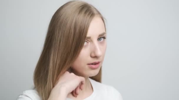 Hermosa mujer en habitación luminosa posando delante de la cámara y jugando con el pelo — Vídeos de Stock