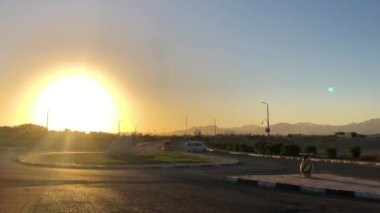 Güneşli Mısır 'da gün batımı. Şeyh Sharm. Palmiye ağaçları, yol, halkalar, mavi gökyüzü