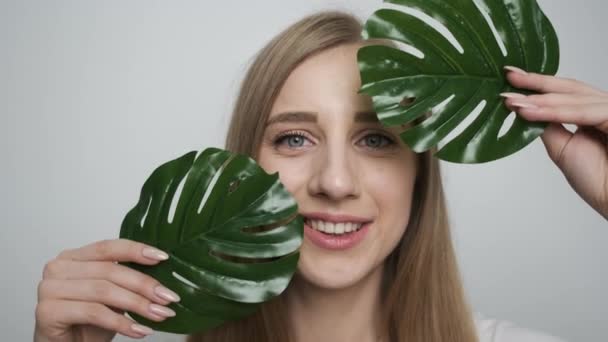 Hermosa chica con una hoja verde posando delante de la cámara — Vídeo de stock