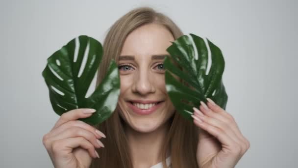 Bella ragazza con una foglia verde in posa davanti alla fotocamera . — Video Stock