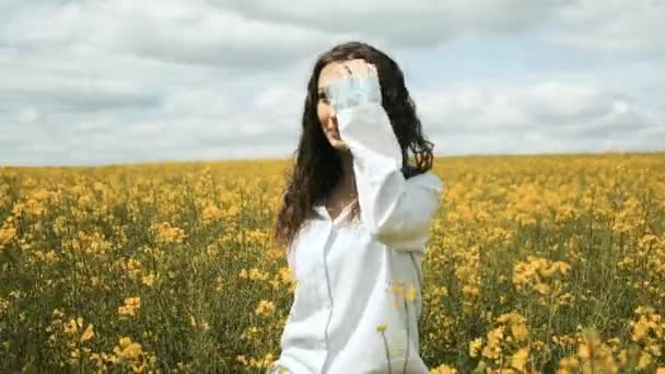 유채 옷을 입은 코카서스 소녀의 쾌활 한 모습. 노란 꽃으로 들판을 가로질러 서 있는 워커들 — 비디오