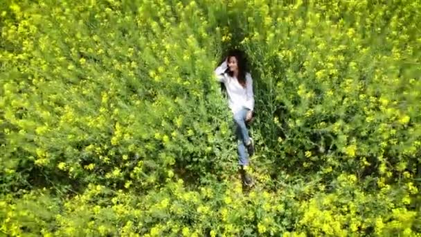 Happy woman of Caucasian appearance lies in a blooming yellow-green field. Spring rape. Drone flight over beautiful nature. Landscapes of Europe — Stock Video