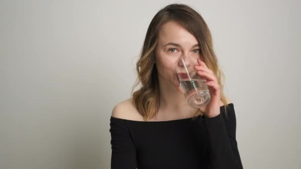 Mulher nutricionista está sentado em uma mesa olhando para legumes e frutas e beber um copo de água limpa — Vídeo de Stock