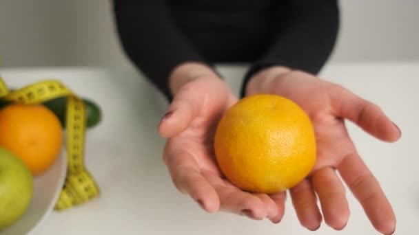 Masadaki kız düzgün bir diyet ve sağlıklı bir yaşam tarzı izliyor. Kamerada portakal servis edilir. Sebzeler ve forumlar masada. — Stok video