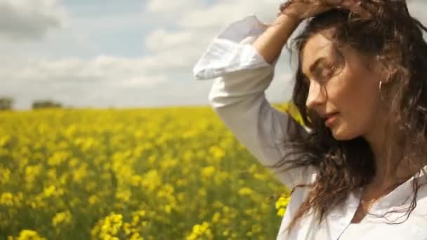 Chica alegre de aspecto caucásico en colza. Disfruta de la naturaleza de las flores amarillas — Vídeos de Stock